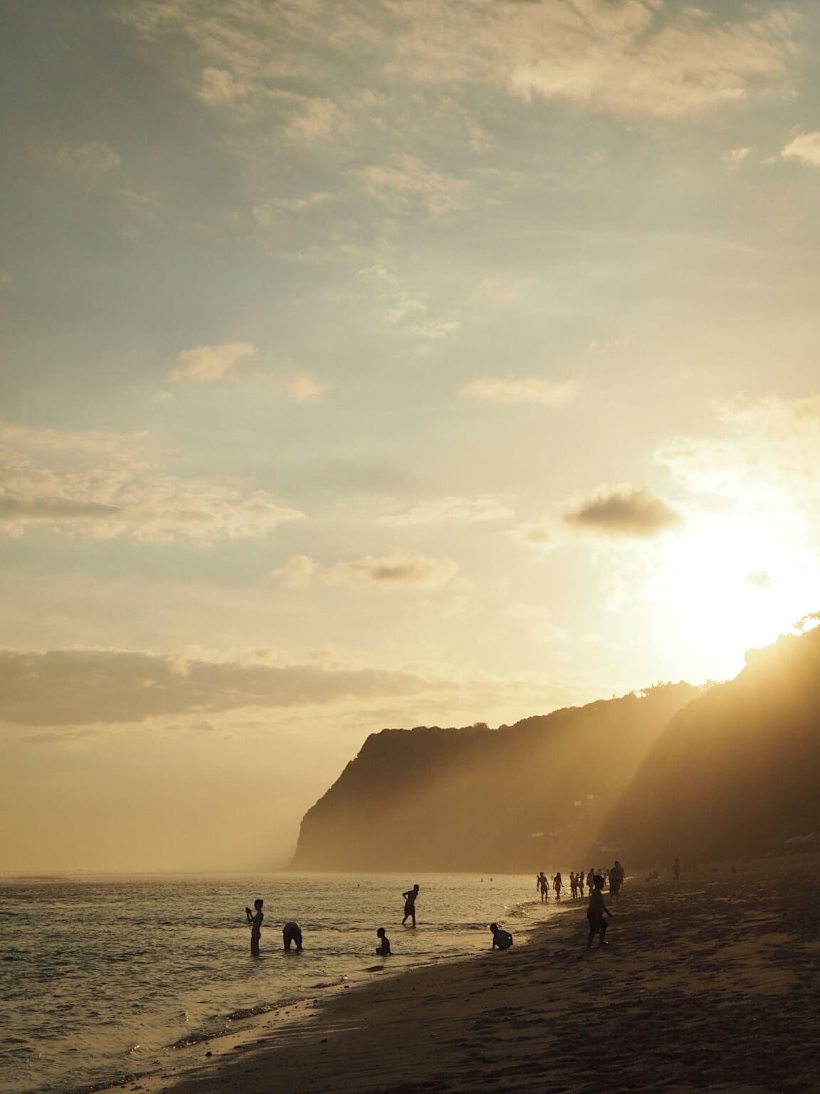 Serene setting, beach with people walking and sunset in background